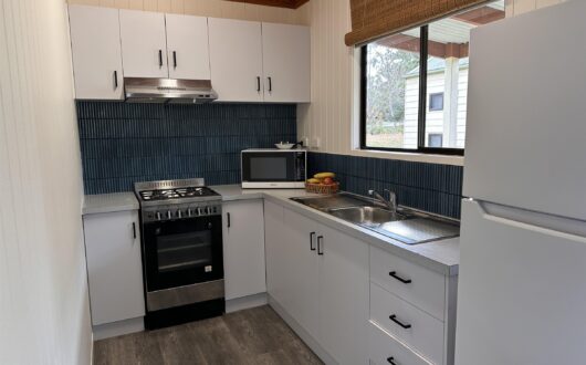 Refurbished cottage kitchen with oven, cooktop, microwave, sink and fridge