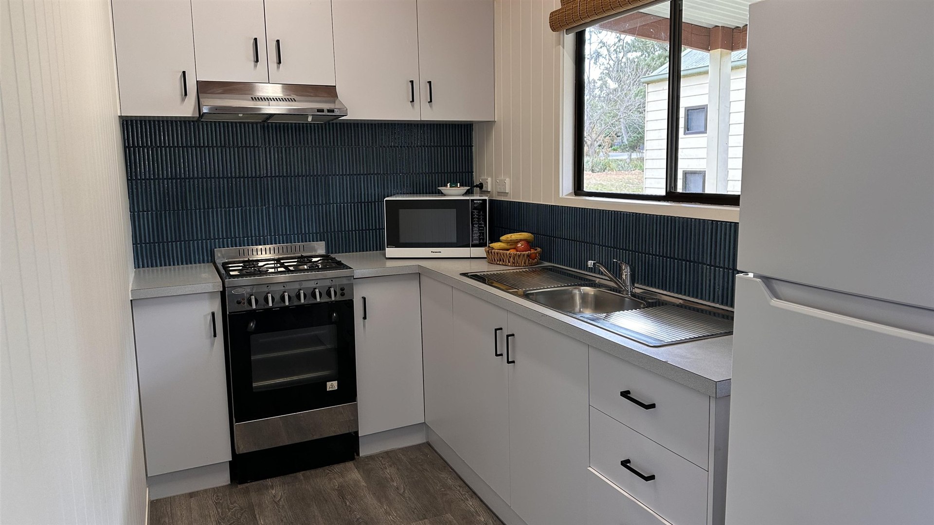 Refurbished cottage kitchen with oven, cooktop, microwave, sink and fridge