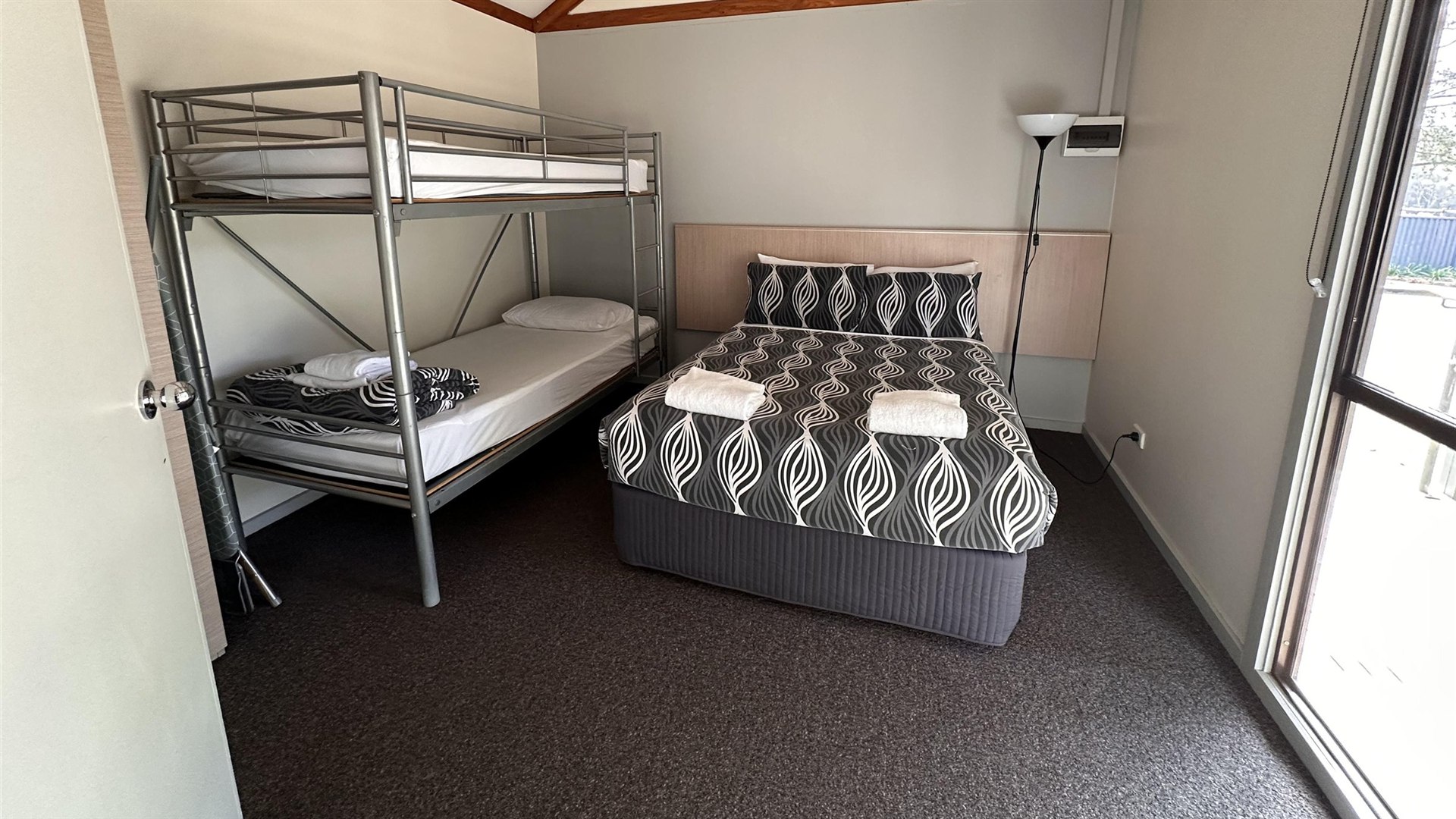 Cabin bedroom with a double bed and a bunk under the raked timber ceiling