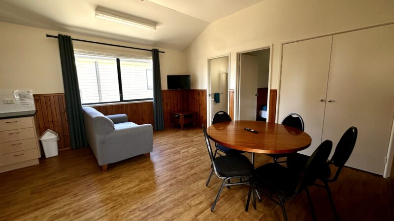 Bungalow living and dining area with a round table, sofa and ceiling fan