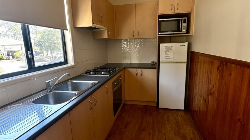 Bungalow galley kitchen with the sink under the window, microwave and fridge
