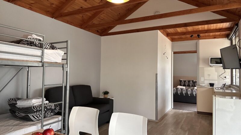 One Bedroom Cabin living area with kitchenette, dining table and bunk beds