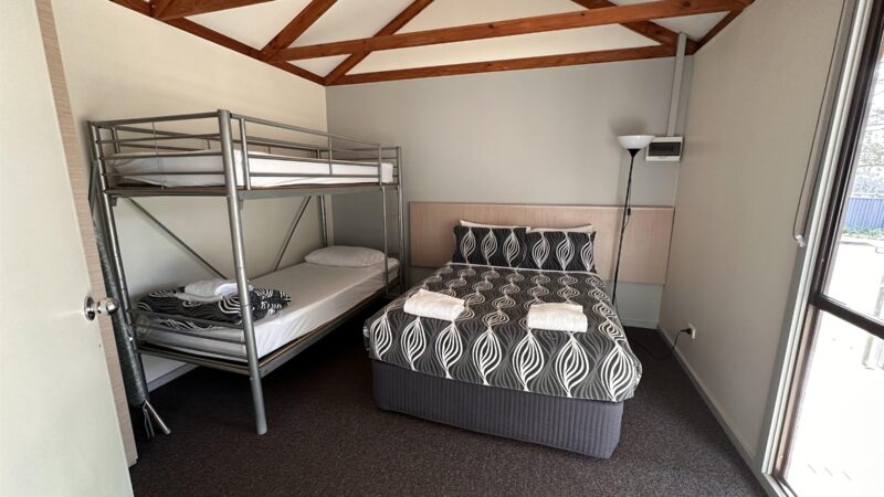 Cabin bedroom with a double bed and a bunk under the raked timber ceiling