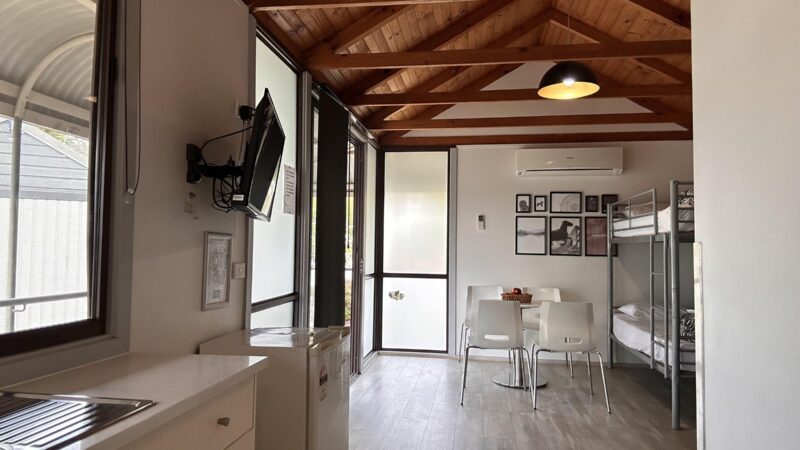 Cabin living area looking through to the kitchenette, with a wall mounted TV