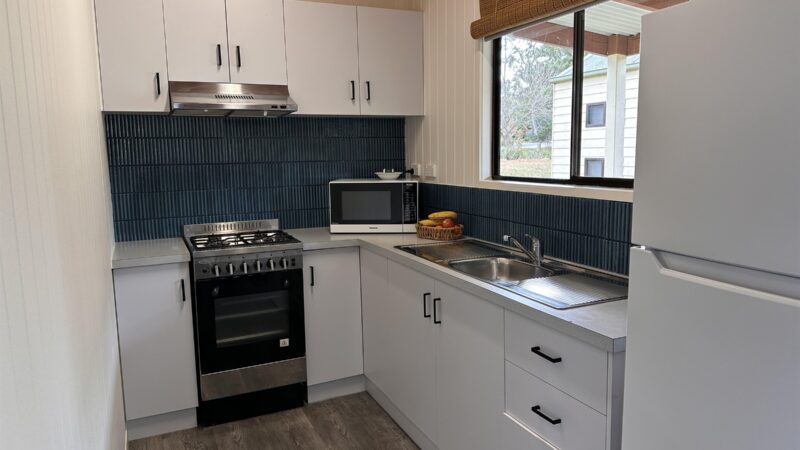 Refurbished cottage kitchen with oven, cooktop, microwave, sink and fridge
