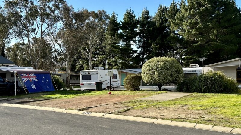 Powered site with a caravan, its awning out and the flag flying